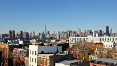 Manhattan skyline seen from Brooklyn, New York City with brick apartment buildings in foreground.